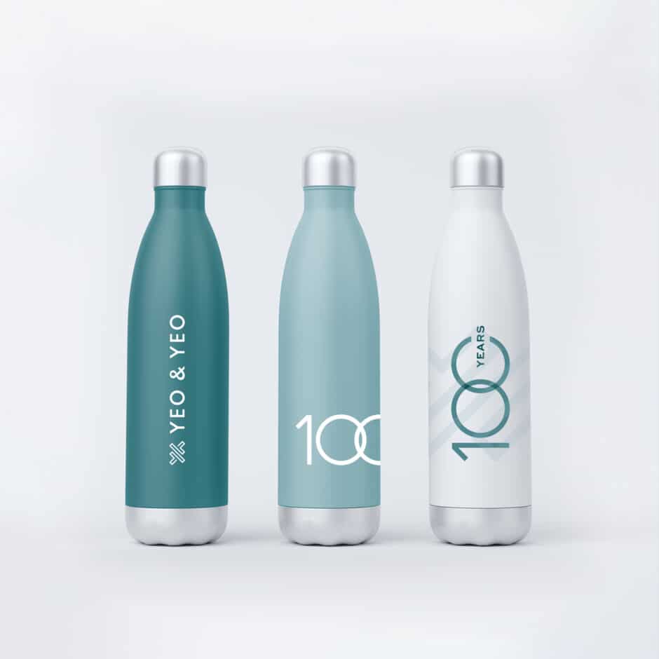 Three sleek reusable bottles in teal and white, with silver caps. They display "YEO & YEO" and "100 Years" text, conveying an elegant, celebratory tone.