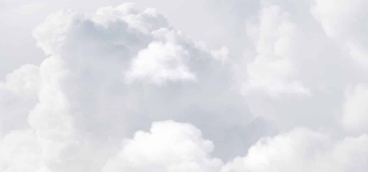 Fluffy white clouds fill the sky, creating a serene and peaceful atmosphere. The soft textures and light tones convey calm and tranquility.